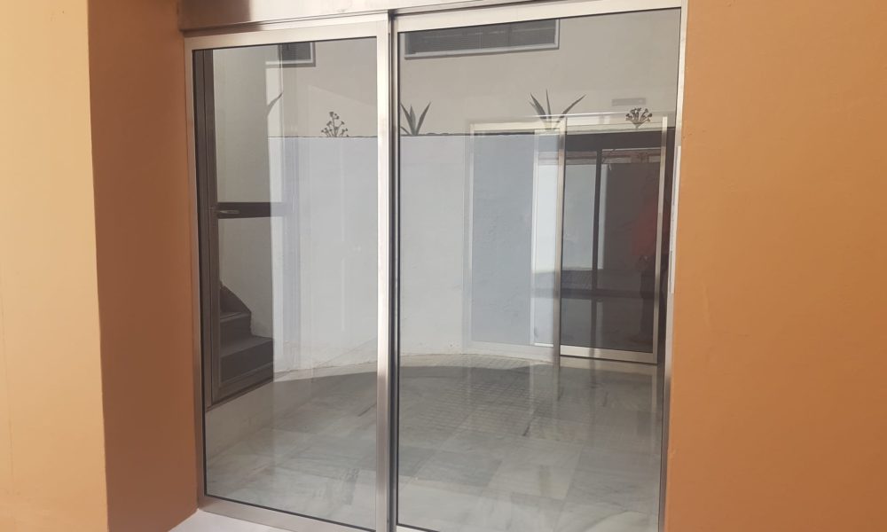 Puerta automática de cristal en Sevillla - Puerta automática de acceso a bloque de viviendas. - Rollmatic
